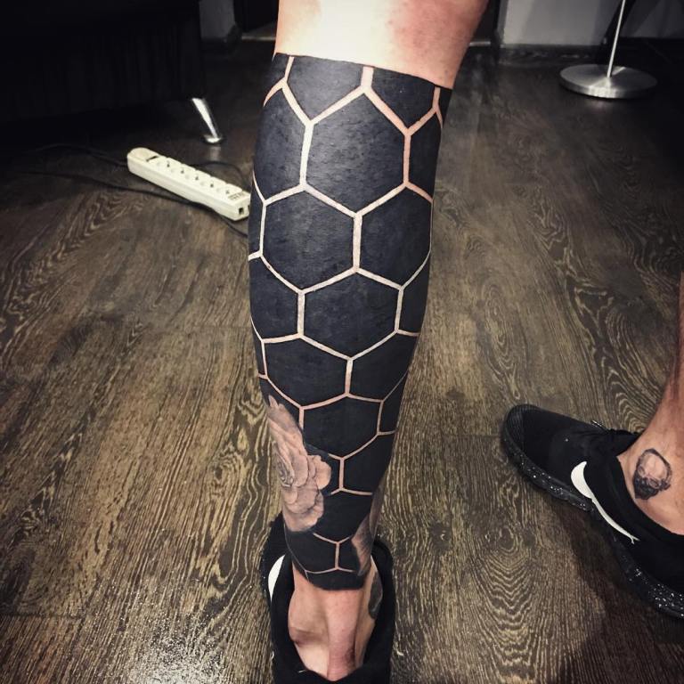 Black tattoo on his leg