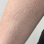 White outline tattoo on arm
