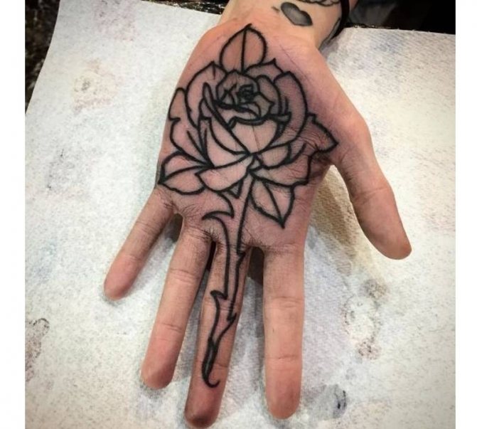 Tattoo of a black rose on his palm