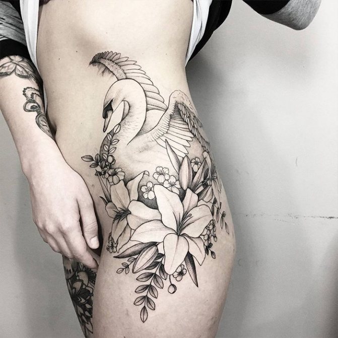 Tattoo of a lily with a swan on her thigh