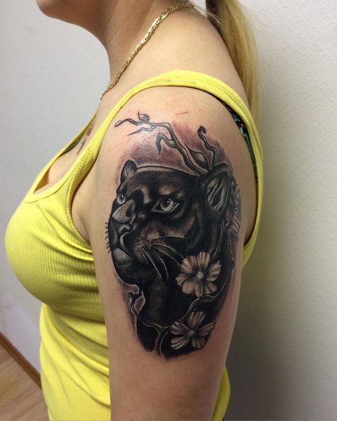 Panther tattoo with flowers on woman's shoulder